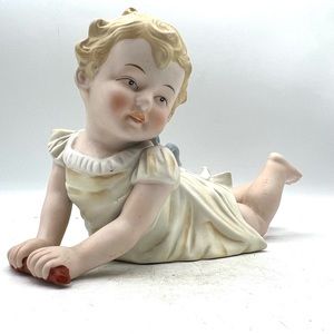 Andrea by Sadek Piano Baby.  Laying on her stomach.   Porcelain Bisque
